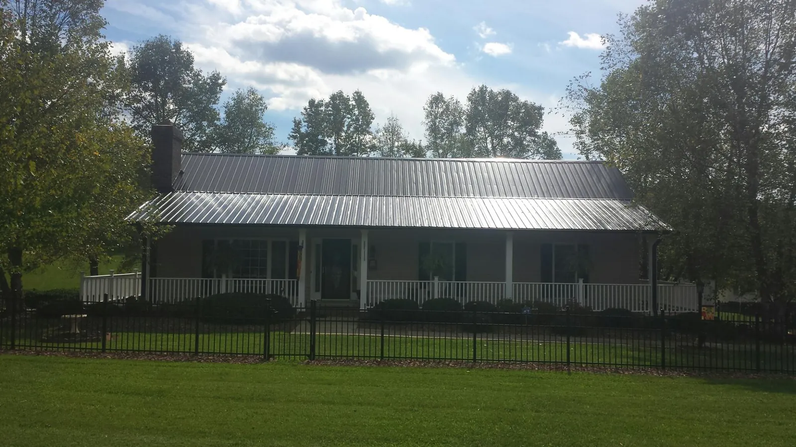 Gray metal roof on a brick ranch with a full width front porch — Gutter Guard Installation work by our crew in Alexandria